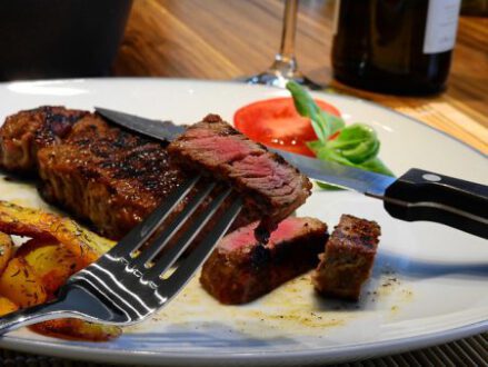 Fleisch_essen-e1574096573464 angeschnittenes Steak auf Teller, mit Gemüsegarnitur