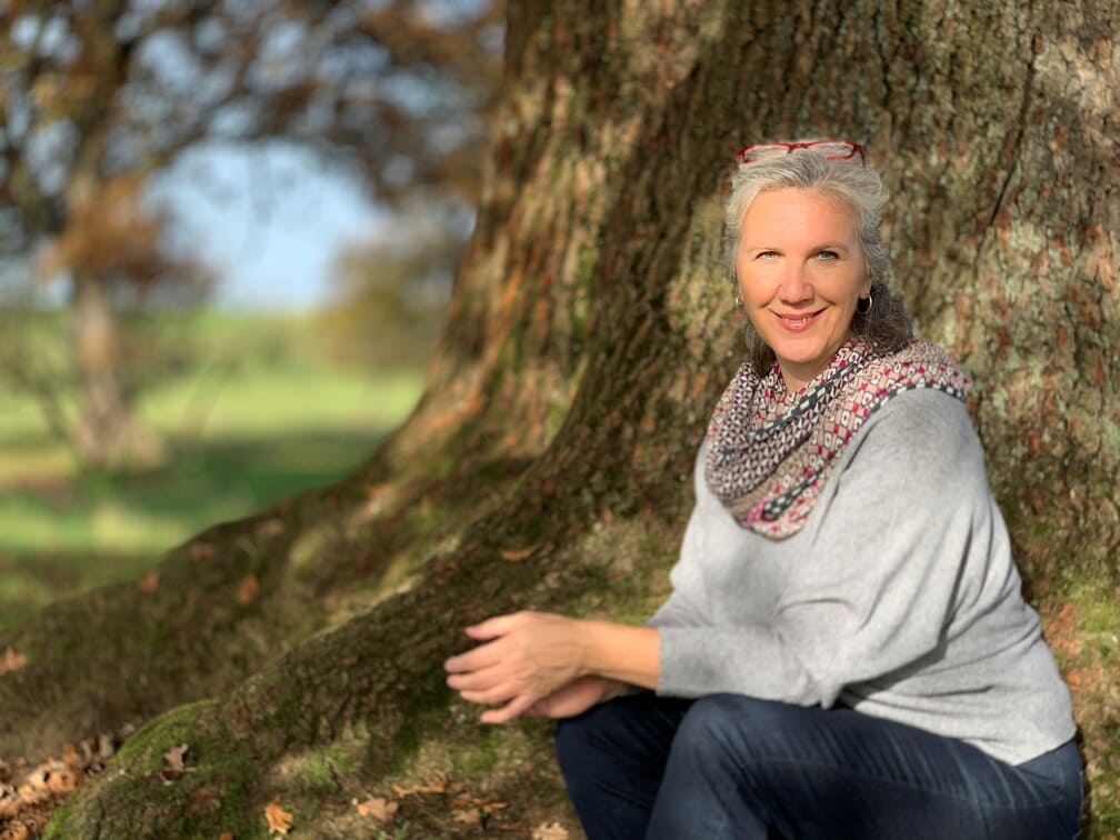 freundliche Frau in der Herbst-Sonne unter einem Baum