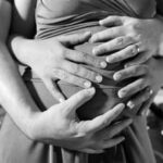 Hände von Vater und Mutter auf dem Bauch der schwangeren Frau, Schüßler Salze für Schwangere