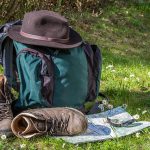 Erholung, Pause für Kiefer und Körper auf einer Wanderung: Rucksack und Wanderstiefel auf einer sonnigen Wiese